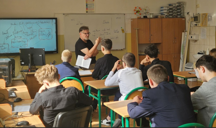 Edukator z Instytutu Pileckiego w klasie przed uczniami prowadzi lekcje. 