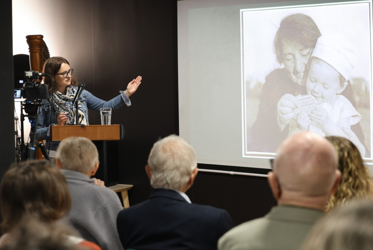 Agnieszka Witkowska-Krych pokazuje na wyświetlane na ekranie zdjęcie Stefanii Wilczyńskiej przytulającej małe dziecko. 