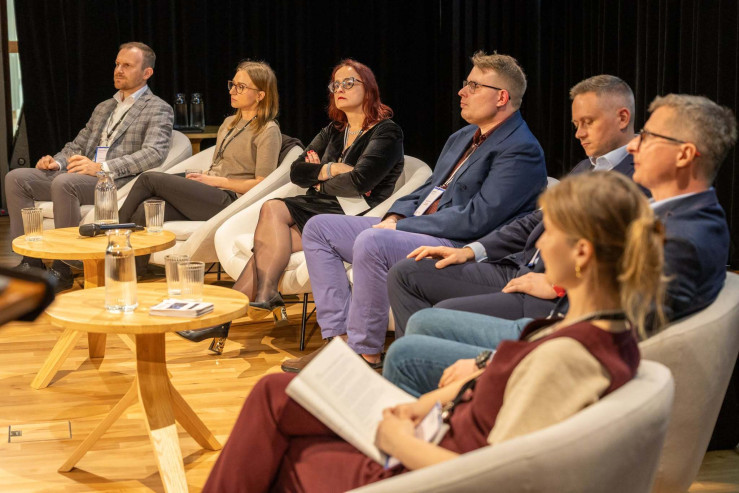 Panel dyskusyjny podczas wydarzenia dotyczącego sztucznej inteligencji w archiwach. Grupa prelegentów siedzi w fotelach na scenie i słucha wystąpienia.