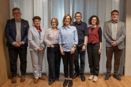 Grupa siedmiu osób pozuje do zdjęcia na stojąco.
