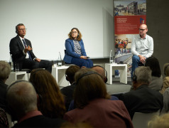 Trzech panelistów na scenie. 